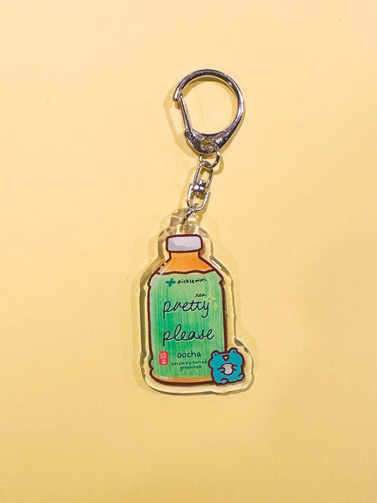 Keychain with green tea bottle and frog design on a yellow background