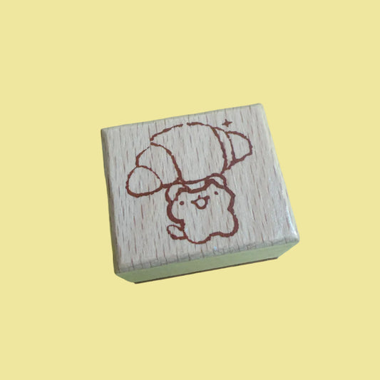 A small wooden rubber stamp with a cute cartoon dog wearing a hat, shown on a light green background.