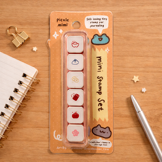 Mini stamp set in packaging on a wooden surface with stationery items.